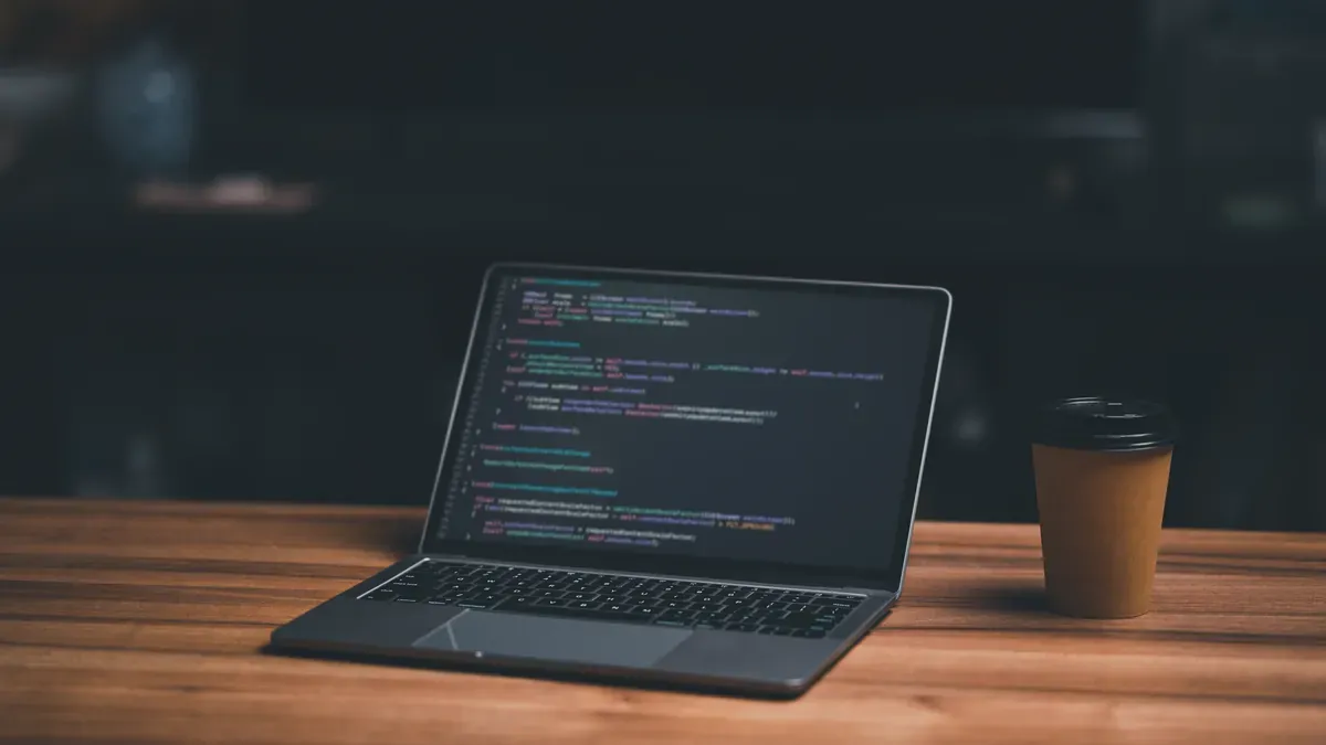 Ahşap masadaki dizüstü bilgisayar ekranında açık duran web sitesi kaynak kodu satırları