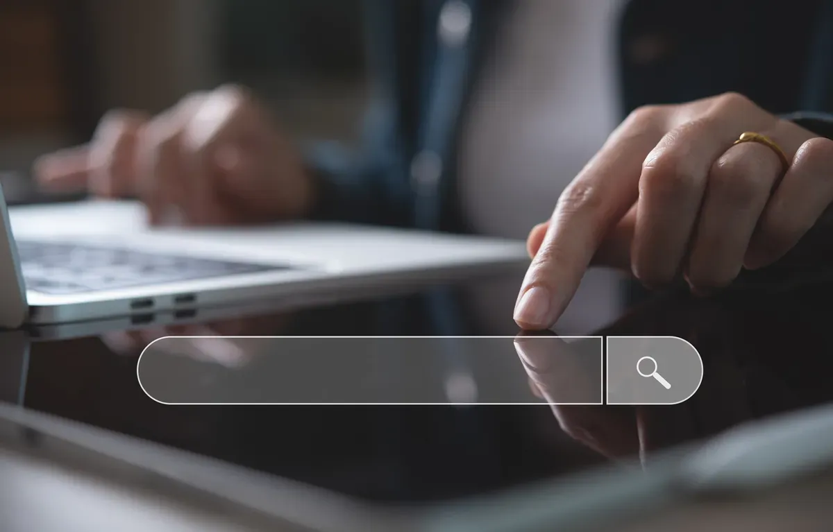 Dizüstü bilgisayar başında ekrandaki boş arama çubuğuna dokunan bir kişi, arama motoru optimizasyonu kavramı