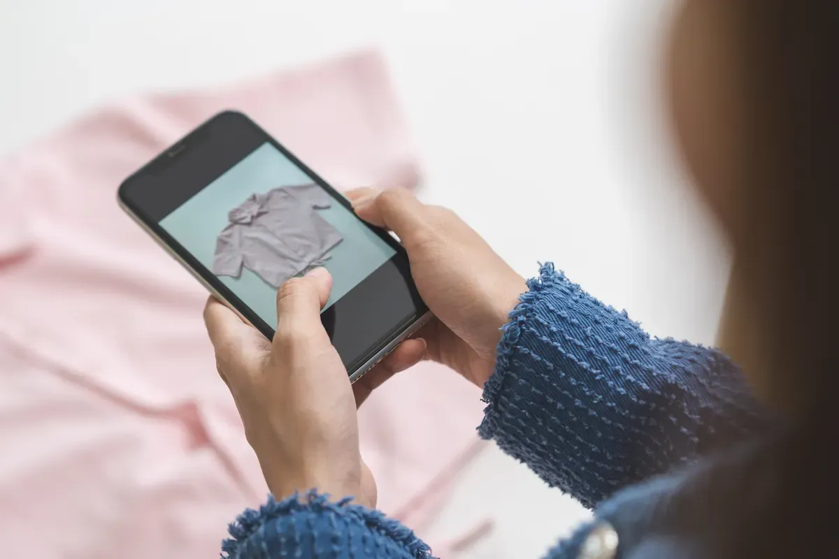 Satışa çıkaracağı kıyafetin fotoğrafını akıllı telefonuyla çeken butik sahibinin elleri