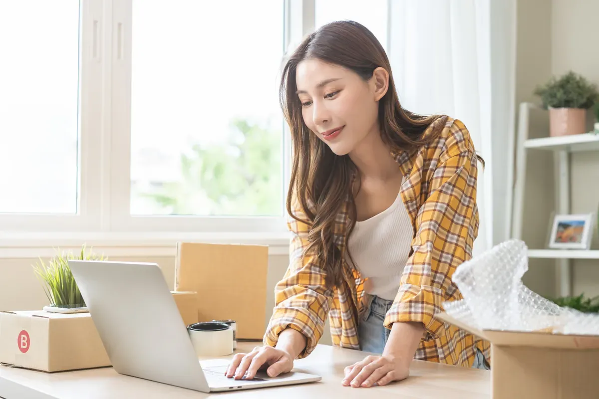 Evdeki çalışma masasında dizüstü bilgisayardan gelen siparişleri kontrol eden online satıcı